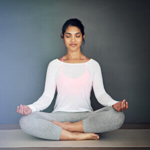 A yoga practitioner sitting cross-legged on a mat with eyes closed