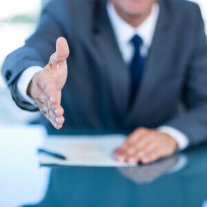 Businessperson reaches across desk to shake hands